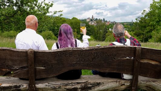 Auf der Bank „Apfelweinkönig 2020“ am Zeilweg genießen Großvater; Enkelin und ein
Bekannter bei einem Schoppen Apfelwein den traditionsreichen Blick über Streuobstwiesen bis
zur Kronberger Burg – ein Stück gelebte Heimat. - Eingereicht von Bernhard Bunte Fotowettbewerb Mammolshain - 20